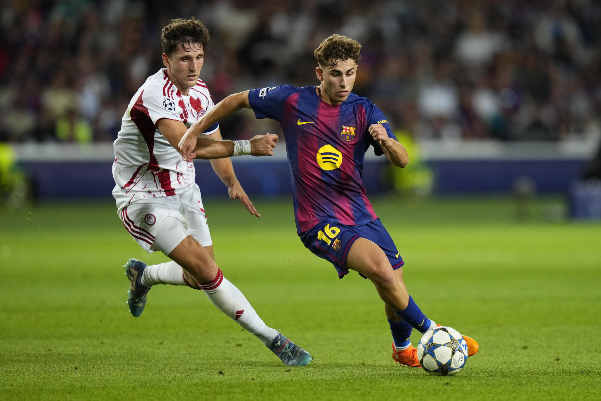 El centrocampista del Barcelona Fermín López (d) disputa un gol con el defensa del Olympiacos Panagiotis Retsos durante el partido de la tercera jornada de la Liga de Campeones que FC Barcelona y Olympiacos FC disputaron en el Estadio Olímpico Lluís Companys. EFE/ Siu Wu