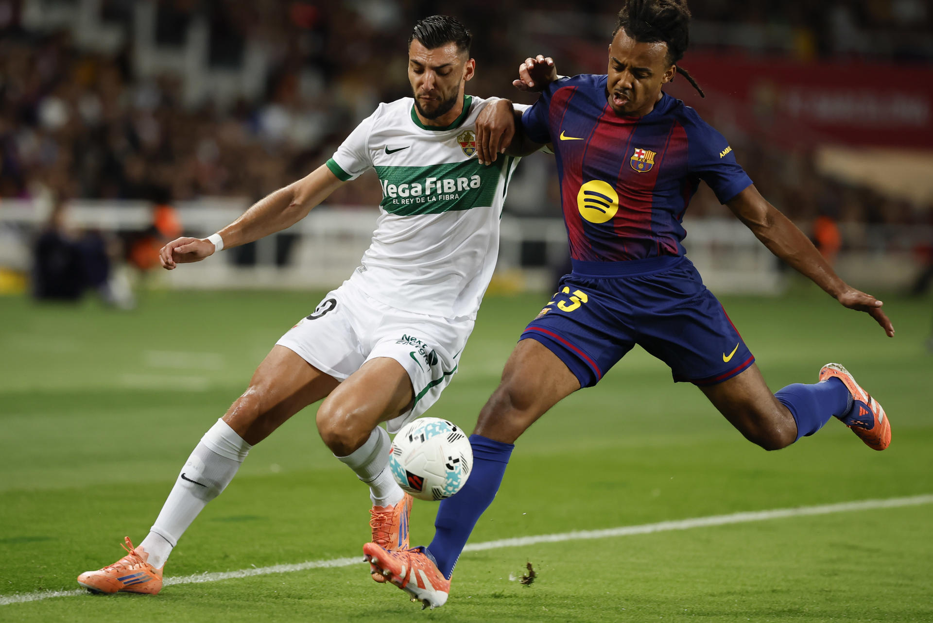 El defensa del Barcelona Jules Koundé (d) lucha con Rafa Mir, del Elche, durante el partido de LaLiga entre el FC Barcelona y el Elche CF, este domingo en el estadio Olímpico Lluis Companys. EFE/Andreu Dalmau