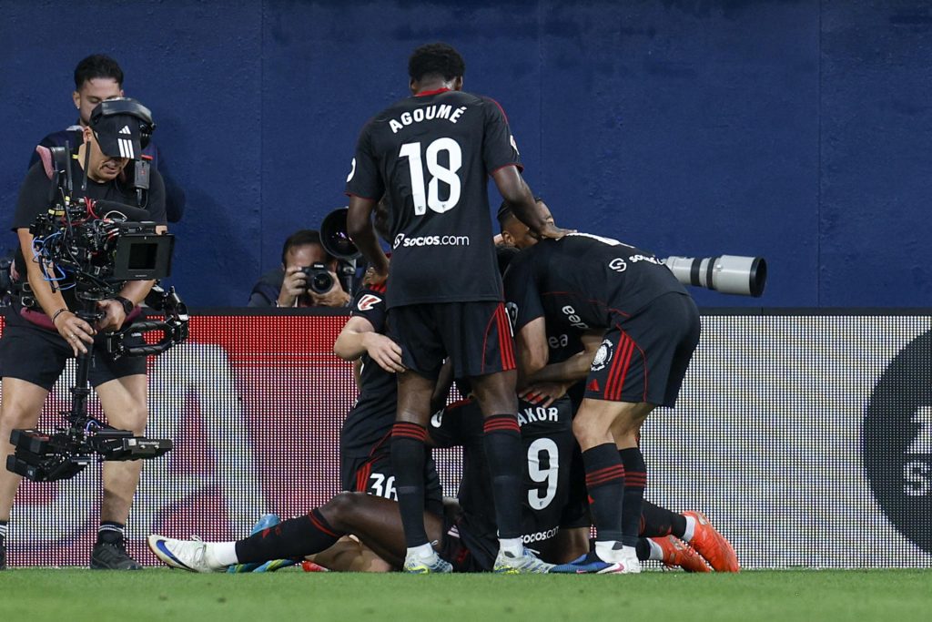El delantero nigeriano del Sevilla FC Akor Adams (en el suelo) celebra junto a sus compañeros tras anotar el 2-3 que adelanta al conjunto hispalense durante el encuentro correspondiente a la jornada 36 disputado este miércoles entre el Villarreal y el Sevilla FC en el estadio de La Cerámica en Villarreal. EFE/ Kai Forsterling

